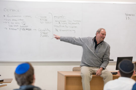 Bob Tufts pointing at the whiteboard to prompt his students.