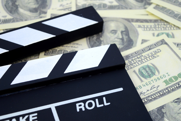 A conceptual image focused on the movie industry and the money it can produce using a clapboard and American cash as a background.